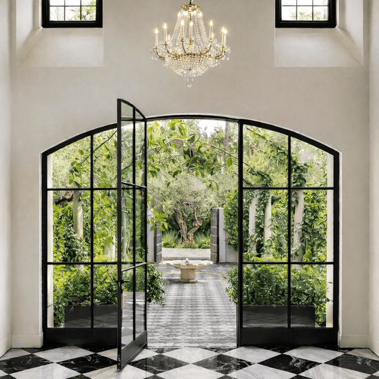 Decorative interior with open glass doors leading to a garden, featuring a chandelier.